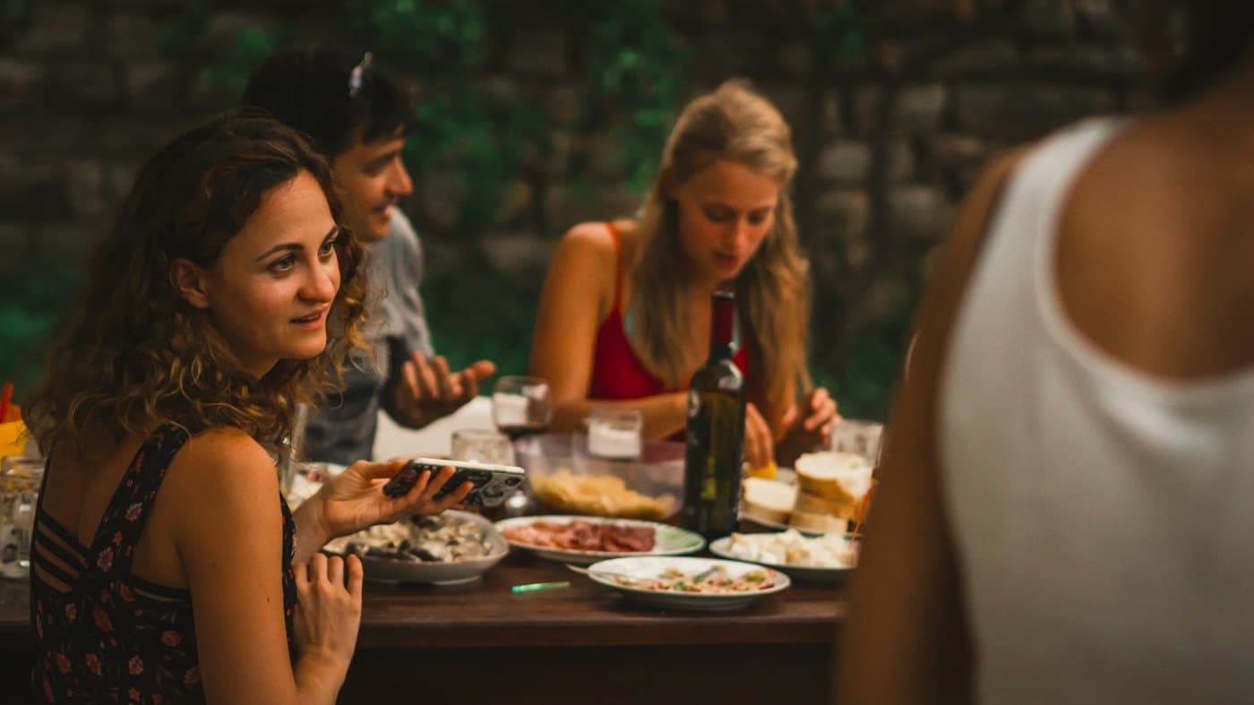 Uzun bir masada akşam yemeği yiyen kalabalık bir grup